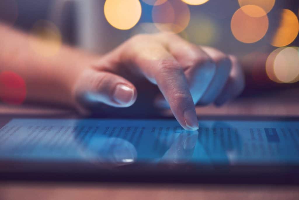 A hand is pointing at a tablet computer screen to provide customer service.