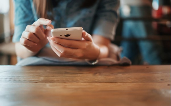 A woman is utilizing communication technology at a table.