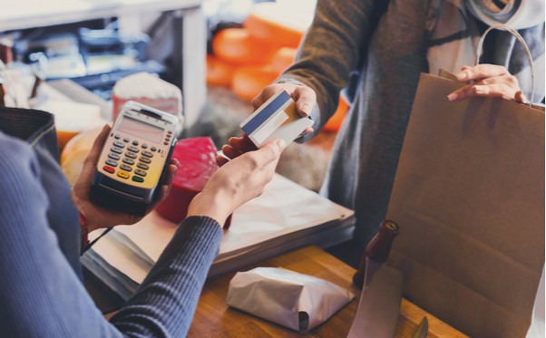 Photo of a person handing over a credit card to make a payment.