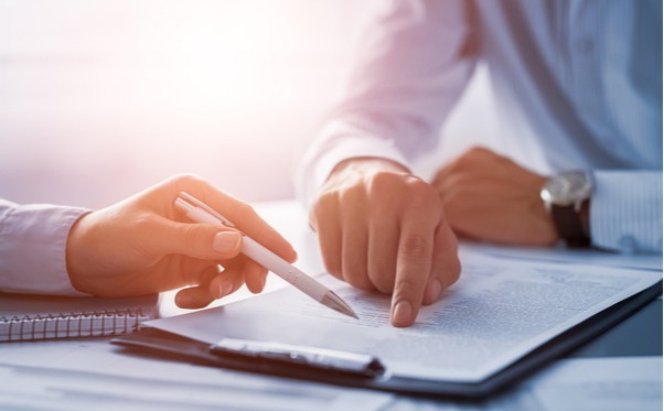 Photo showing hands pointing at a paper document