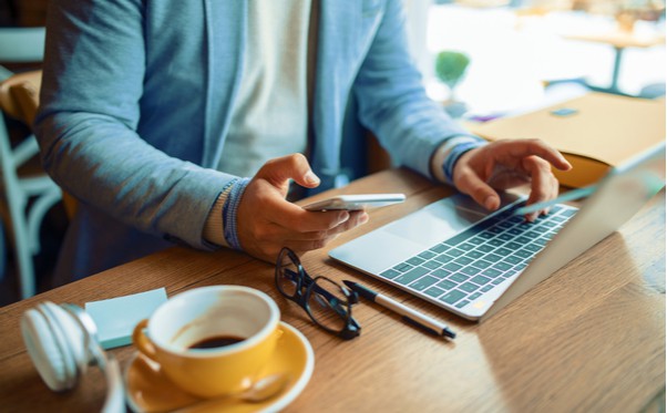 A man using customer agent lifecycle tools at a table with a laptop and cell phone.