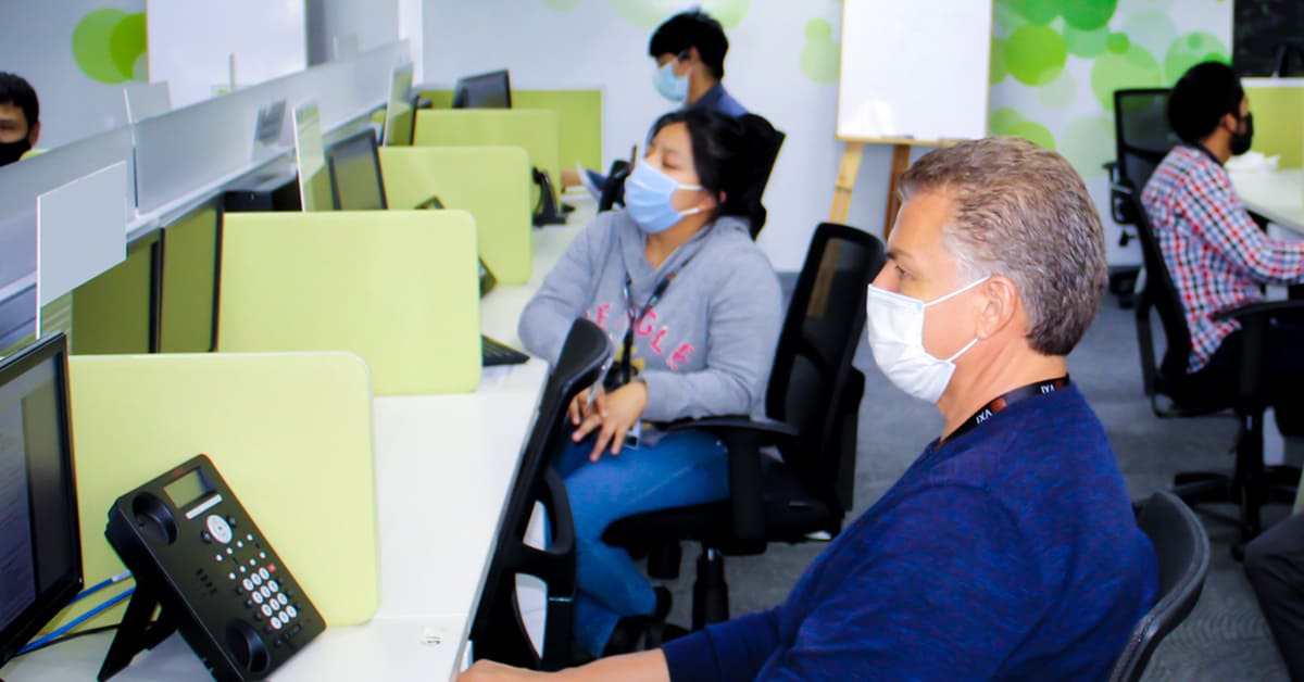 A team of VXI call center employees wearing protective face masks while working